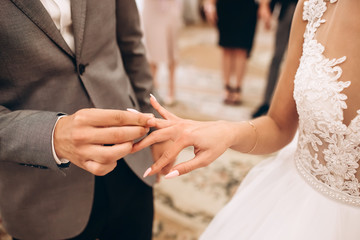 Wall Mural - The bride and groom wear wedding rings. A young couple at a wedding ceremony. hands closeup.