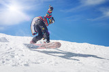 Freerider snowboarder rolls and rides his snowboard on extreme gradient downhill. Winter mountain freeride