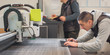 © guruXOX - Two printshop worker technicians works on large CNC computer numerical control printing and cutting machine