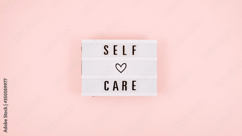 Self-care word on lightbox and flower narcissus on pink background flat lay. Take care of yourself. - obrazy, fototapety, plakaty 