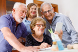 Gruppo famigliare di nonni  felici che fanno una videochiamata verso persone care dal salone di casa