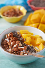 Wall Mural - mango and greek yoghurt with seeds and nuts on wooden surface