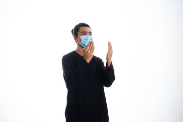 An Asian young man isolated on white background with casual entire and wearing a face mask. Hand gesture stop, sick, respect. during coronavirus 