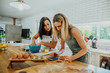 © Prins Productions - Young mother and daughter baking in kitchen and checking recipe on smartphone