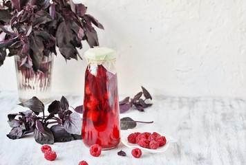 Poster - homemade raspberry vinegar with purple basil and garlic. In a bottle on a light background. copy space