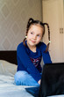 © Гульнара Мандрыкина - the girl is sitting on the bed next to the laptop and looks away