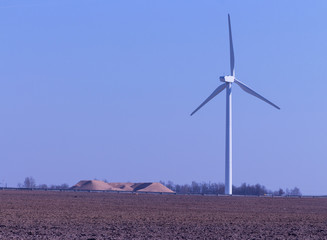 Wind generator far on the horizon, alternative electricity concept. Against the blue sky