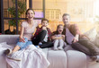 © deniskomarov - Happy laughing parent with kid watch funny movie sitting on couch in home living room.