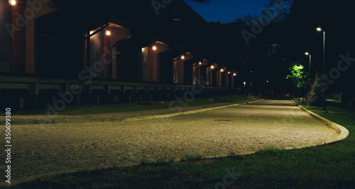 Nocne zdjęcie brukowanej drogi, latarnie i szereg drzwi Białystok, podlaskie,...