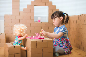 Wall Mural - toddler girl pretend play baby care in a carton house