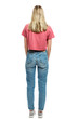 © Анна Демидова - A young girl in jeans and a red T-shirt is standing. Back view. Full height. Isolated on a white background. Vertical.