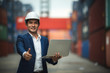 © chokniti - Portrait of a company executive in a warehouse, industrial port area that shows containers for international exports.