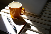 Yellow Cup Of Coffee On A Desk With A Calendar And A Pen.