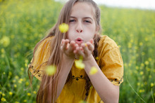 Beautiful Young Girl Blowing Kisses And Flowers (Dandelions) In A Field