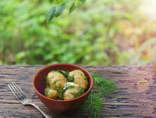 Canvas Print - Young boiled potatoes with butter and dill on a wooden background of an old tree. country style. Organic food. copy space