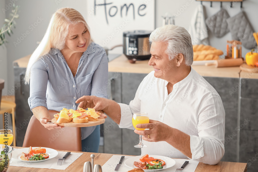 Happy elderly couple having breakfast at home