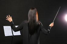 Young Female Conductor On Dark Background