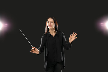 Young female conductor on dark background