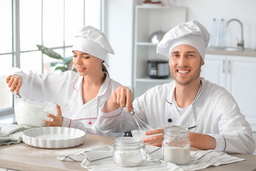 Canvas Print - Young confectioners cooking tasty dessert in kitchen