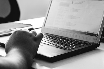 Wall Mural - Young woman hand typing on laptop in desk in office (in black and white)