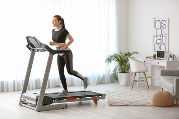 Sporty young woman training on treadmill at home