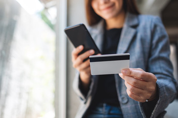 Wall Mural - A beautiful asian woman using credit card for purchasing and shopping online on mobile phone