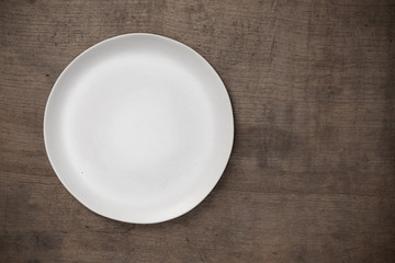 Blank white ceramic round dish on wooden desk blackground with copy space, Flat lay of traditional handcrafted kitchenware concept