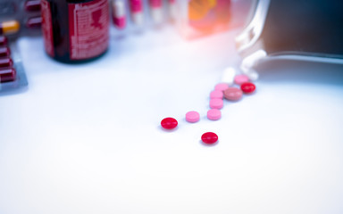 Poster - Red tablets pills on blurred background of tablets, stainless steel drug tray, and vitamin bottle. Pharmaceutical industry. Pharmacy drugstore products. Healthcare and medicine concept. Pharmaceutics.