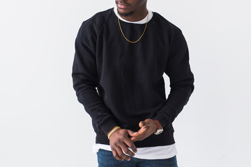Wall Mural - Close-up of black man dressed in jeans and sweatshirt on white background. Street fashion and modern youth culture.