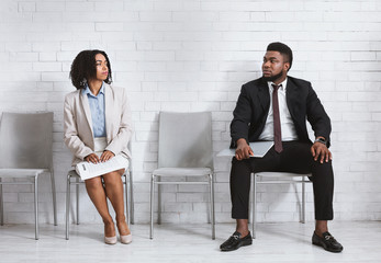 Wall Mural - Male and female vacancy candidates looking at each other with antipathy while waiting for job interview in office hall