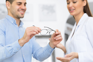Fototapete - Optometrist helping man to choose correction glasses