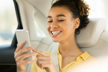 Happy Woman Using Smartphone Sitting On Back Seat In Car