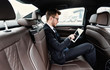 © Prostock-studio - Young businessman using his laptop in luxury car
