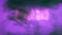 Black Liquid Ink Drops Splash Swirling And Mixing In Colored Purple Water Background. Effect Of Abstract Smoke Explosion Animation. Slow Motion Footage. Close-up.