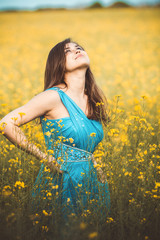 Sticker - beautiful romantic girl on blooming rapeseed field enjoying nature, happyoung elegant woman walking, looking to heaven with love and gratitude