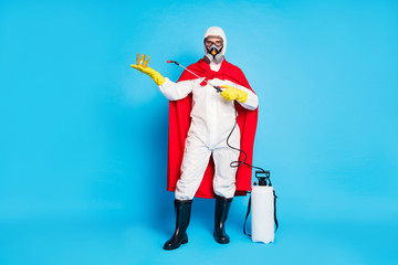 Wall Mural - Full length photo of strong power man doctor disinfect gold crown covid virus infection use spray equipment wear yellow latex gloves goggles mantle white suit isolated blue color background