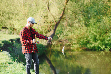 Wall Mural - young fisherman fishes near the river. The concept of outdoor activities and fishing