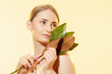 Wall Mural - Close up of beautiful young woman with green leaves on white background. Concept of cosmetics, makeup, natural and eco treatment, skin care. Shiny and healthy skin, fashion, healthcare.