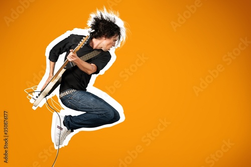 Male guitarist playing music on guitar and jump
