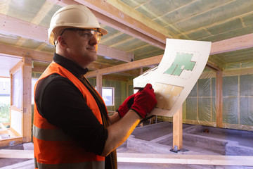 Poster - construction of cottages. a man inside a house under construction. builder with room plans in hand. 