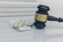 Drugs And Law. Judge Gavel And Colorful Pills On A Wooden Desk, Dark Background, Closeup View.