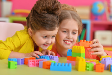 Wall Mural - Two little girls playing with colorful plastic blocks