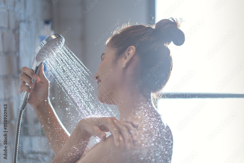 Asian woman is taking a shower and rubbing her shoulders - obrazy, fototapety, plakaty 