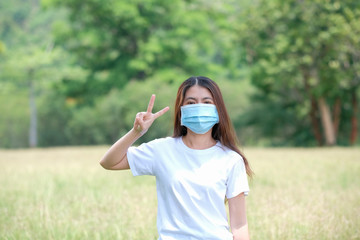 Asian women wear protective masks to protect against viruses. Raise two fingers to resist the virus. Covid 19