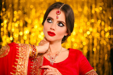 Canvas Print - Portrait of beautiful indian girl in red bridal sari over golden bokeh. Young hindu woman model with kundan jewelry. Traditional Indian costume lehenga choli. Henna painting, mehendi on bride's hands.