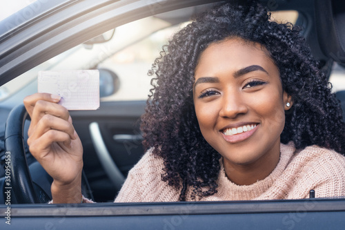 Cuadros en Lienzo Young black woman at the wheel showing driving license
