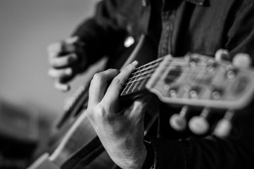 Guitar player chords close up on the strings - black and white, selective focus.