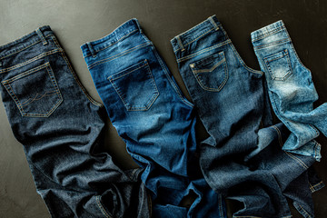 Wall Mural - Clothing - family jeans on black. Various denim trousers from above.