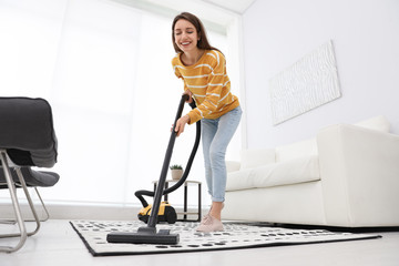 Poster - Young woman using vacuum cleaner at home