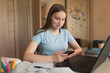© byswat - Happy smiling girl teenager, home in hand smartphone, laptop lessons. E-education distance learning Internet video communications. Writes reads a message, social networks on the Internet.